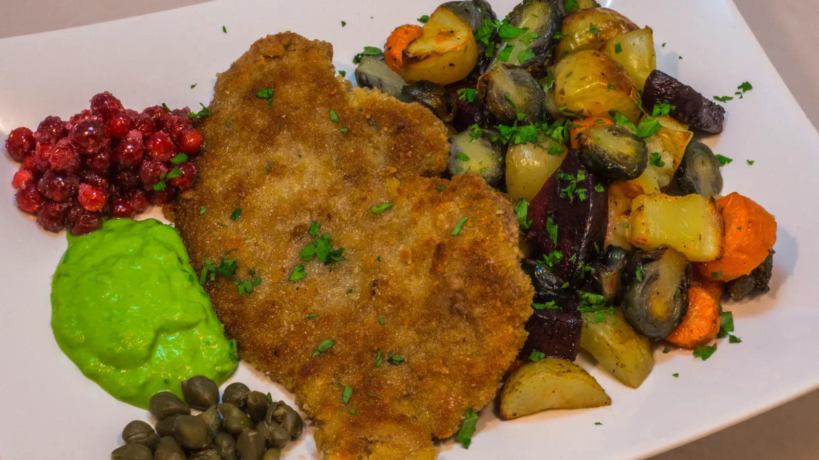 Wild boar schnitzel with roasted root vegetables and pea purée